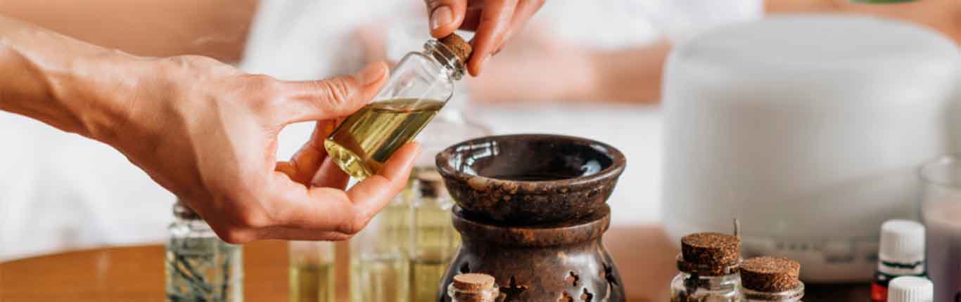Aromatherapy massage, pouring aromatic oil in essential oil diffuser